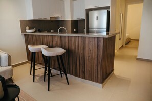 Eine moderne Küche mit einer Holzinsel, zwei Barhocker, einem Edelstahlkühlschrank und weißen Schränken.
