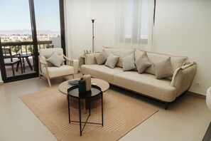 Ein modernes Wohnzimmer mit einer Couch, Sesseln, einem Couchtisch und einem Essbereich mit Tisch und Stühlen.
