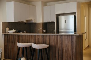 Una cocina moderna con una isla central, electrodomésticos de acero inoxidable y detalles de madera.