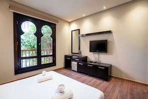 Ein Hotelzimmer mit Bett, Fernseher, Kommode und Fenster mit Blick auf Grünflächen.