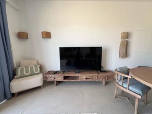 A living room with a flat-screen TV, a wooden entertainment unit, a sofa, and a dining table with chairs. - Kamaran 2BR • Luxurious Retreat (Hurghada)