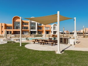 A resort with a pool, outdoor seating, and a building with multiple balconies. - Kamaran 2BR • Luxurious Retreat (Hurghada)
