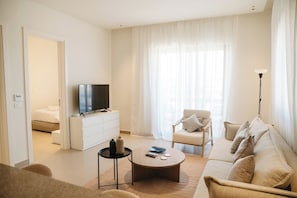 Una sala de estar moderna con televisor, sofá, sillón y una mesa de centro.