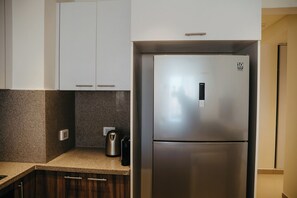 Eine moderne Küche mit einem Edelstahl-Kühlschrank, weißen Schränken, Granit-Arbeitsplatten und einer Kaffeemaschine.