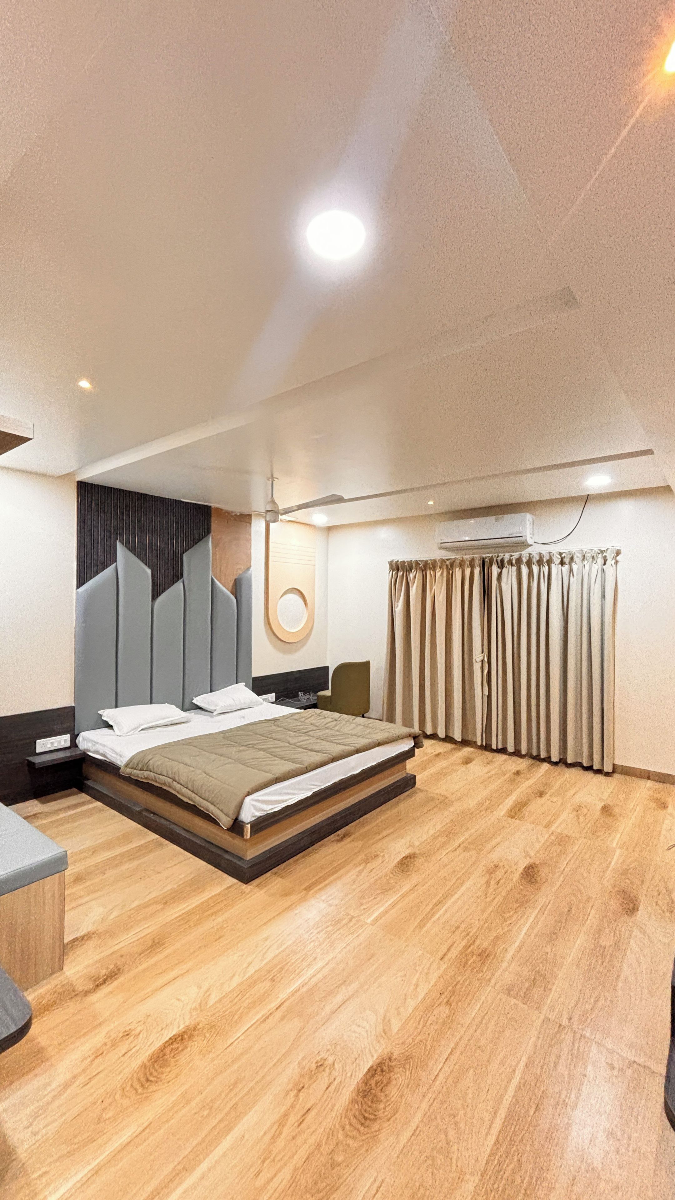 A modern bedroom with a large bed, a ceiling fan, and a wall-mounted air conditioning unit.