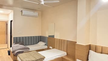 Habitación de hotel con dos camas, ventilador de techo y aire acondicionado.