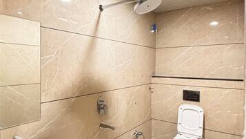 A bathroom with a shower, toilet, sink, and a bucket.