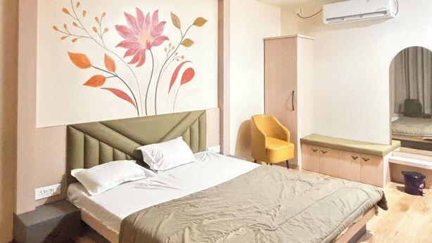 Un dormitorio moderno con cama, aire acondicionado de pared y ventilador de techo, además de un elemento decorativo en la pared.