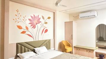A modern bedroom with a bed, a wall-mounted air conditioner, a ceiling fan, and a decorative wall piece.