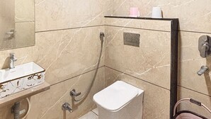 Un baño con lavamanos, inodoro, ducha y espejo.