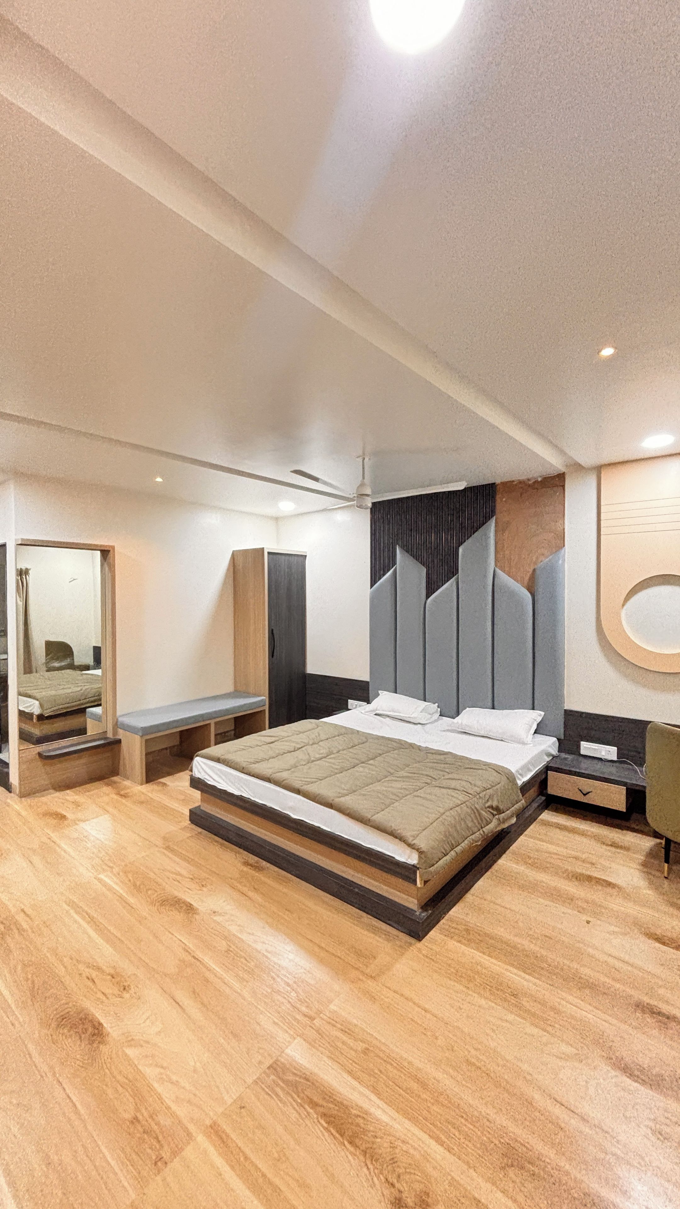 Un dormitorio moderno con una cama grande, una mesita de noche, un armario y un espejo.