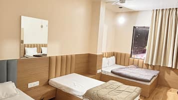 Habitación de hotel con dos camas, ventilador de techo, ventana con cortinas y un espejo en la pared.