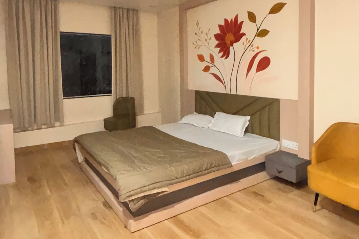 A bedroom with a bed, a nightstand, a chair, a window with curtains, and a ceiling fan.