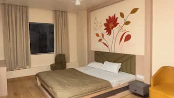 Un dormitorio con cama, mesita de noche, una silla, ventana con cortinas y ventilador de techo.