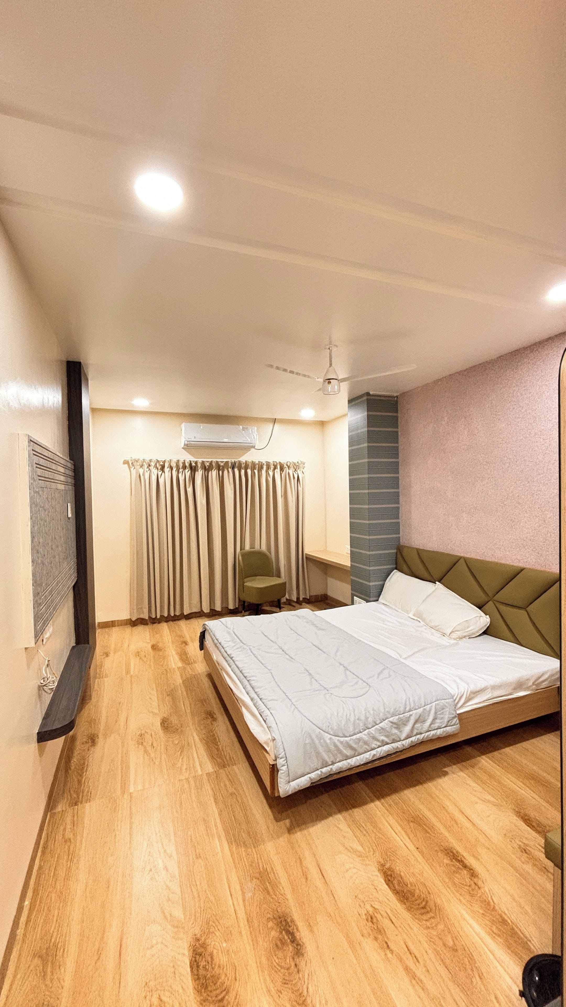Ein Schlafzimmer mit einem Bett, einem Sessel, einer Klimaanlage und einem Deckenventilator.