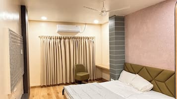 Ein Schlafzimmer mit einem Bett, einem Sessel, einer Klimaanlage und einem Deckenventilator.
