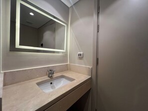A bathroom with a rectangular sink, a mirror with a light, and a wall-mounted light switch. - Beachside Mangroovy 1BR (Red Sea)