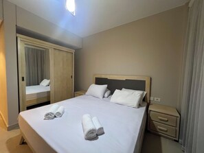 Quarto de hotel com cama, duas mesas de cabeceira, guarda-roupa e espelho.