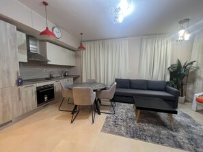 A modern kitchen with a dining area, a sofa, and a plant. - Beachside Mangroovy 1BR (Red Sea)