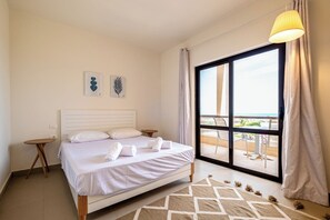 A hotel room with a bed, a small table, a window with a view, and a hanging light fixture. - Fanadir 3BR • Prime Sea View Villa (Hurghada 2)