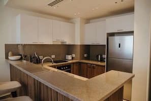Una cocina moderna con encimera de granito, electrodomésticos de acero inoxidable y armarios de madera.