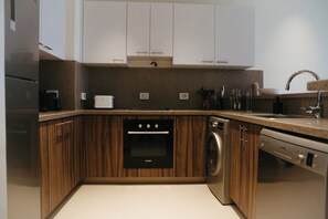 Eine moderne Küche mit Holzausstattung, einem Bosch-Ofen, einer Waschmaschine und einem Spülbecken.
