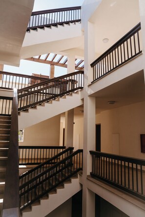Un interior de varios niveles con una escalera central, varios balcones y un diseño arquitectónico moderno.