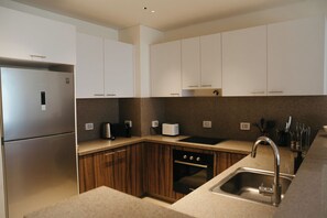 Una cocina moderna con refrigerador de acero inoxidable, gabinetes de madera, horno empotrado y pileta con grifo.