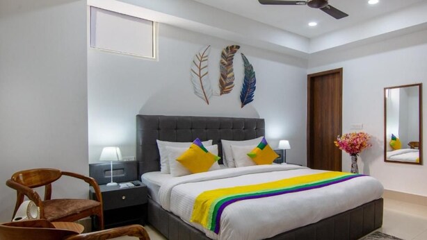 Un dormitorio con una cama grande, dos mesitas de noche, una silla, un ventilador de techo y decoración en la pared.