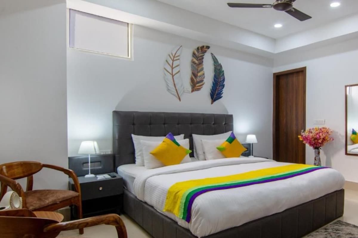 A bedroom with a large bed, two bedside tables, a chair, a ceiling fan, and decorative wall art.