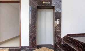 Ascensor con pared de mármol y un cartel que indica el primer piso.