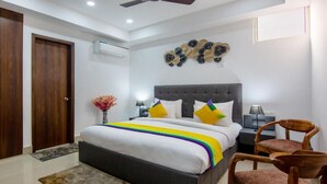 Un dormitorio con una cama, un ventilador de techo, un adorno en la pared y una mesita de noche con una lámpara.