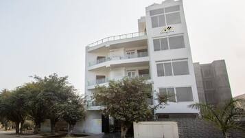 Un immeuble à plusieurs étages doté de balcons, d’un toit plat et d’une enseigne indiquant qu’il s’agit d’un hôtel.