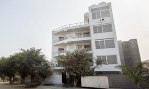 Un edificio de varios pisos con balcones, techo plano y un letrero que indica que es un hotel.