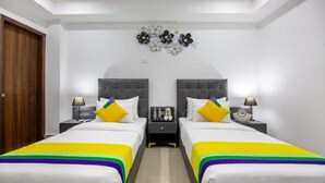 Habitación de hotel con dos camas, una mesita de noche con lámpara y un adorno en la pared.