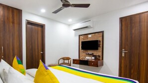 Un dormitorio con cama, armarios de madera, ventilador de techo, unidad de aire acondicionado y televisor montado.