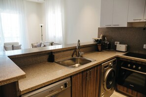 Una cocina moderna con lavavajillas integrado, un fregadero, una estufa y un tostador.