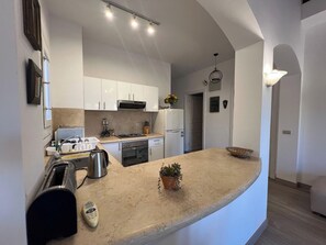 A modern kitchen with white cabinetry, a central island, and a built-in oven. - Cozy South Marina 2Bdr with Pool Access (Red Sea)