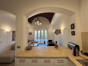 A kitchen with a central island, a dining area with a sofa, and a view through an archway to a living room. - Cozy South Marina 2Bdr with Pool Access (Red Sea)