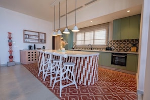 A modern kitchen with a central island, bar stools, pendant lights, and patterned flooring. - The Reef House Luxury Waterfront Villa (El Gouna Hurghada)