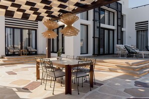 An outdoor dining area with a stone floor, a wooden table, and chairs. - The Reef House Luxury Waterfront Villa (El Gouna Hurghada)