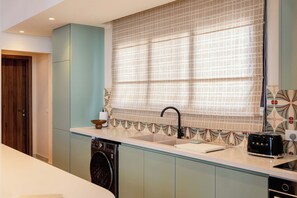 A kitchen with a built-in dishwasher, a sink with a modern faucet, and a toaster on the countertop. - The Reef House Luxury Waterfront Villa (El Gouna Hurghada)