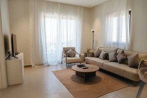 Una sala de estar moderna con un sofá, un sillón, una mesa de centro y un televisor de pantalla plana.