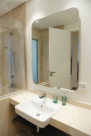 Ein Badezimmer mit Dusche, Waschbecken und Spiegel.