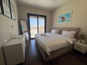 A hotel room with a bed, bedside tables, a desk, and a view through a glass door. - Cyan Luxe Retreat 3BR Townhouse with Lagoon View (Hurghada 2)