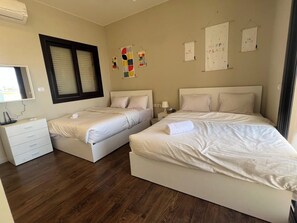 Ein Schlafzimmer mit zwei Betten, einem Schminktisch und einem Fenster mit Jalousien.