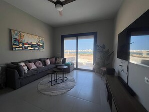 Ein modernes Wohnzimmer mit einer Couch, einem runden Couchtisch und einem Fernseher.