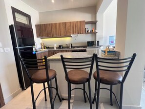 Een moderne keuken met een vast geïntegreerd eiland, houten kastjes en een zwarte koelkast.