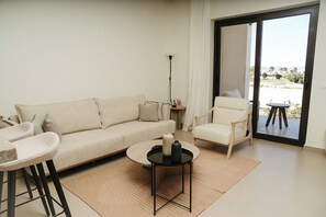 Una sala de estar moderna con un sofá, un sillón, una mesa de centro y vistas a través de un ventanal.