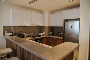Una cocina moderna con encimera de granito, electrodomésticos de acero inoxidable y armarios de madera.
